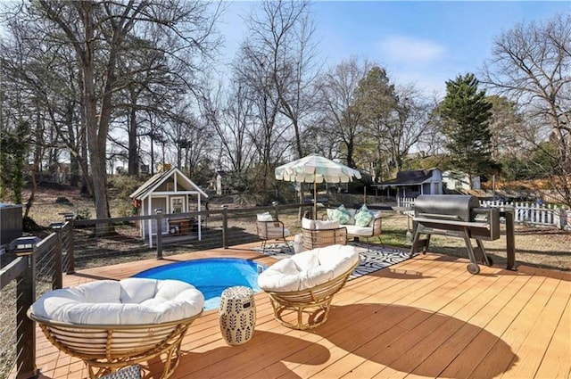 view of pool with a wooden deck, an outbuilding, and view of scattered trees