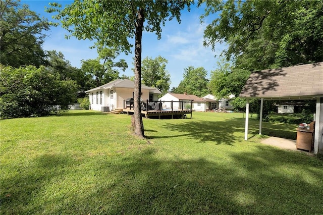 view of green lawn featuring a wooden deck and central AC