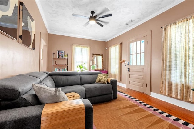 living room featuring light wood-style flooring, ceiling fan, plenty of natural light, crown molding, and baseboards