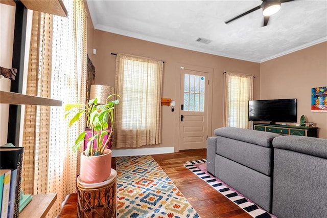 living area with wood finished floors, a ceiling fan, and crown molding
