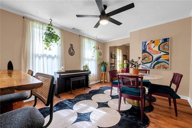dining space with wood finished floors, ceiling fan, ornamental molding, and baseboards