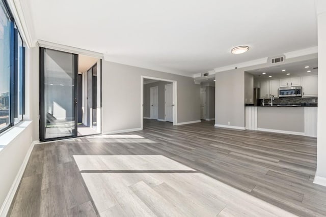 unfurnished living room featuring wood finished floors, visible vents, and baseboards