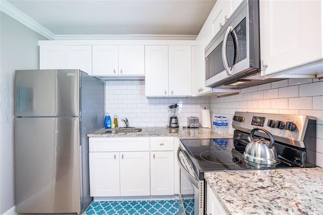 kitchen with ornamental molding, decorative backsplash, a sink, white cabinets, and appliances with stainless steel finishes