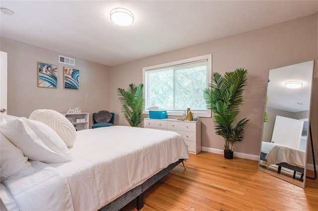 bedroom with visible vents, light wood-type flooring, and baseboards