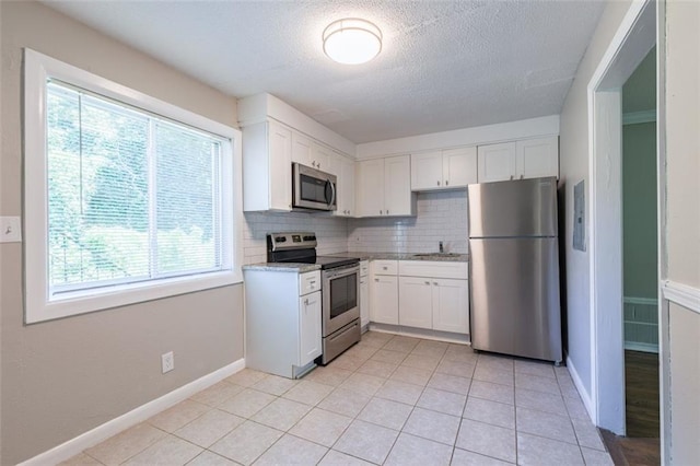 kitchen with white cabinetry, a sink, tasteful backsplash, and stainless steel appliances