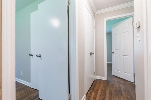 corridor with dark wood finished floors, crown molding, and baseboards