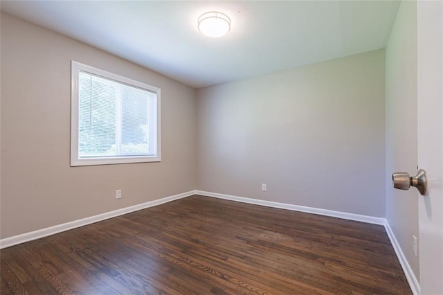 unfurnished room featuring baseboards and dark wood-style floors