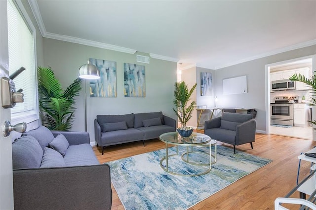 living room with visible vents, plenty of natural light, crown molding, and light wood-style floors