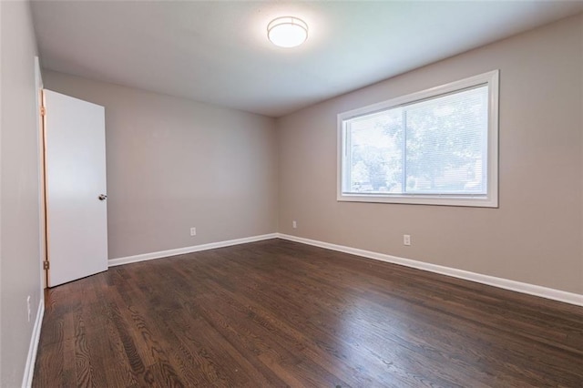 unfurnished room with baseboards and dark wood finished floors