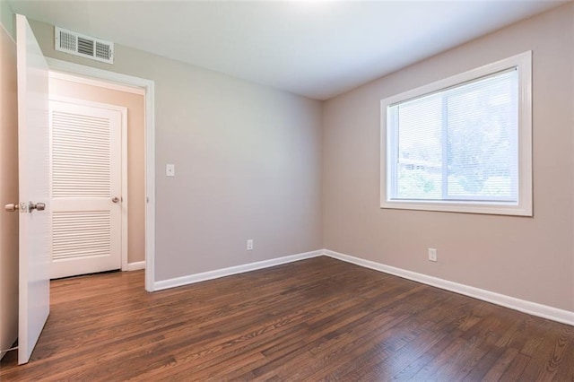 spare room featuring baseboards, visible vents, and dark wood-style flooring