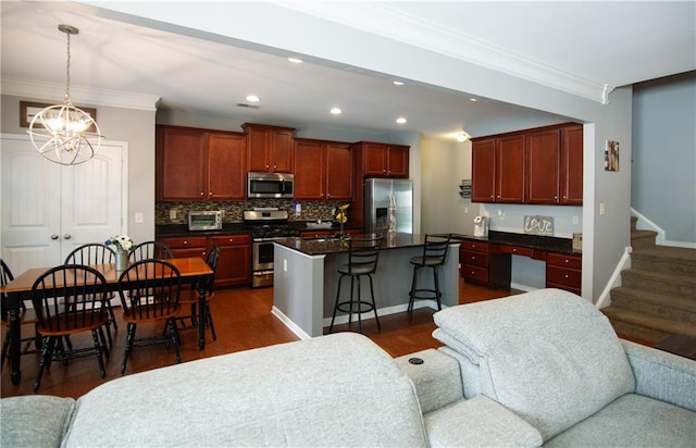 kitchen featuring appliances with stainless steel finishes, dark countertops, ornamental molding, open floor plan, and recessed lighting