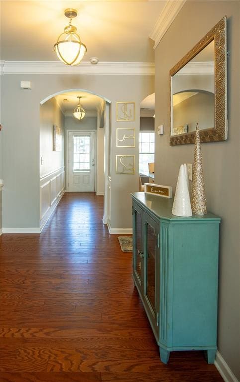 foyer with arched walkways, ornamental molding, dark wood-style flooring, and baseboards