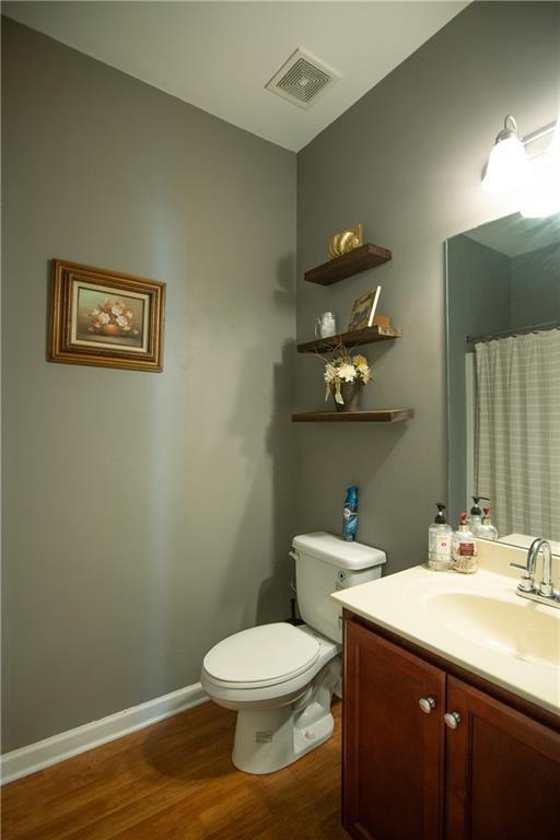 full bathroom with wood finished floors, vanity, toilet, a shower with shower curtain, and baseboards