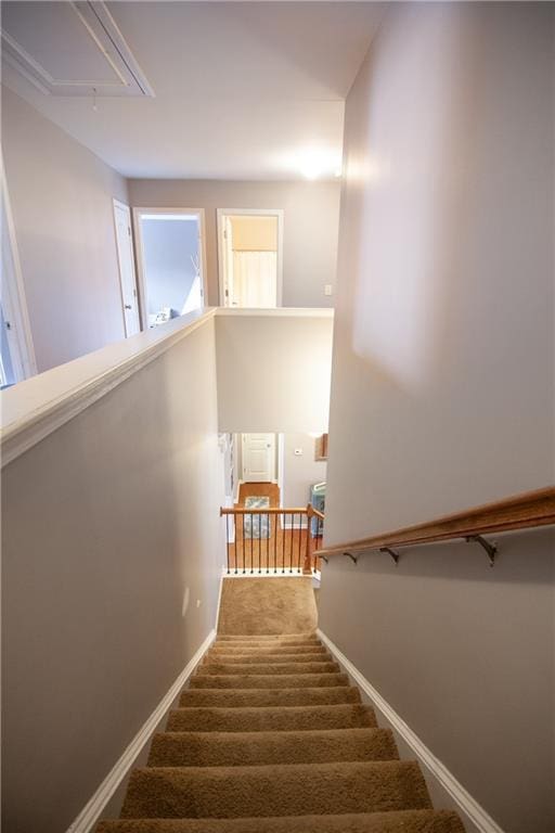 stairway with attic access, carpet floors, and baseboards