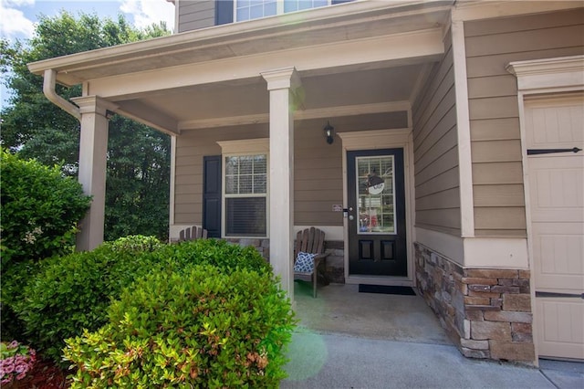 doorway to property with a porch and stone siding