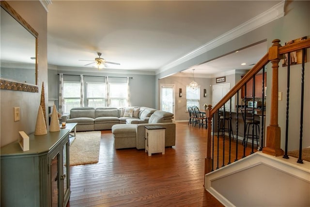 living area featuring stairs, ornamental molding, a ceiling fan, dark wood-style floors, and baseboards