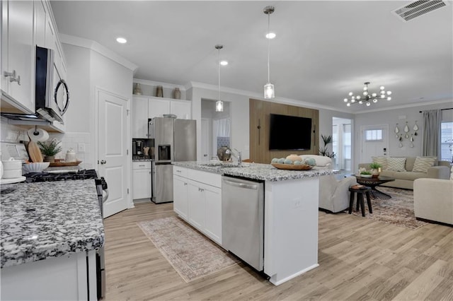 kitchen featuring visible vents, a sink, appliances with stainless steel finishes, open floor plan, and a center island