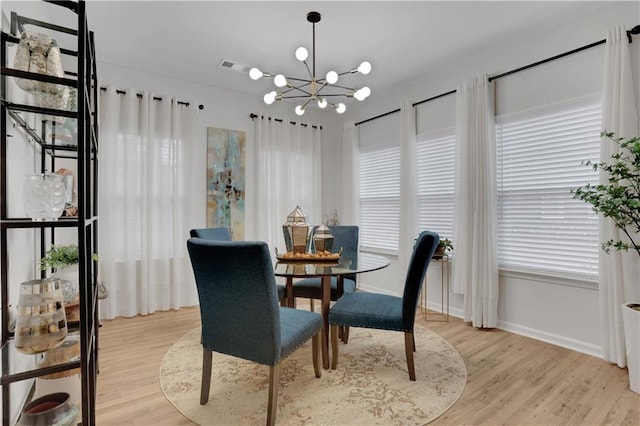 dining area featuring baseboards, a notable chandelier, and light wood finished floors