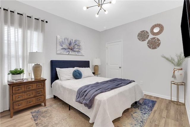 bedroom featuring baseboards, a notable chandelier, and light wood-style flooring