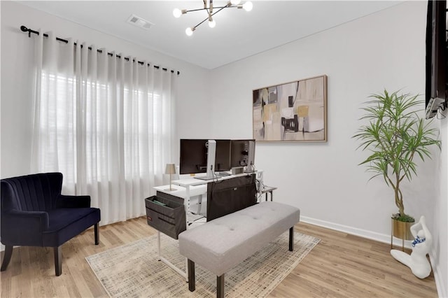 living area with a chandelier, visible vents, light wood finished floors, and baseboards