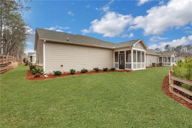 back of house featuring a lawn and a sunroom