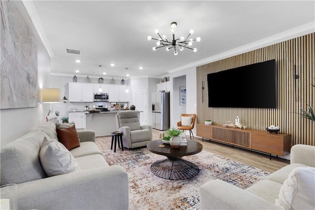 living room with visible vents, crown molding, recessed lighting, light wood-style floors, and an inviting chandelier