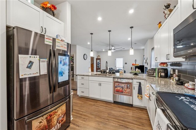 101 Marion Dr, Cartersville, GA 30120 - kitchen with appliances with stainless steel finishes, a peninsula, white cabinetry, light stone countertops, and decorative light fixtures