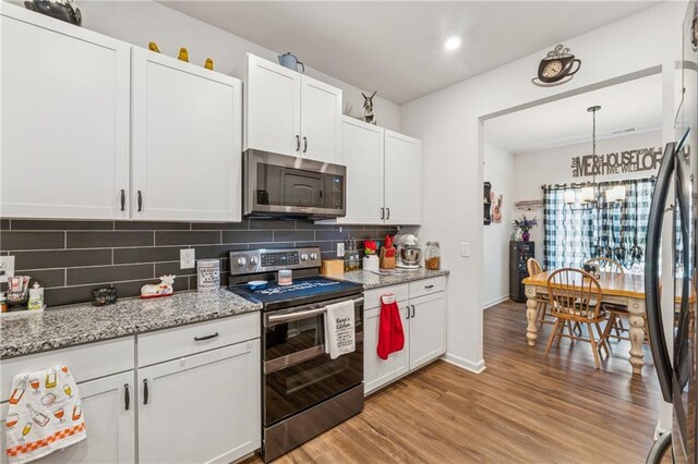 101 Marion Dr, Cartersville, GA 30120 - kitchen with stainless steel appliances, light wood-type flooring, decorative backsplash, white cabinets, and light stone counters