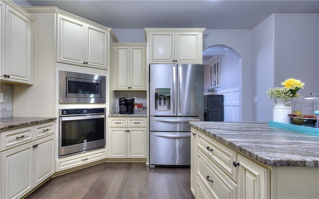 116 Chorley Run, Ellenwood, GA 30294 - kitchen with stainless steel appliances, arched walkways, backsplash, dark wood-type flooring, and light stone countertops