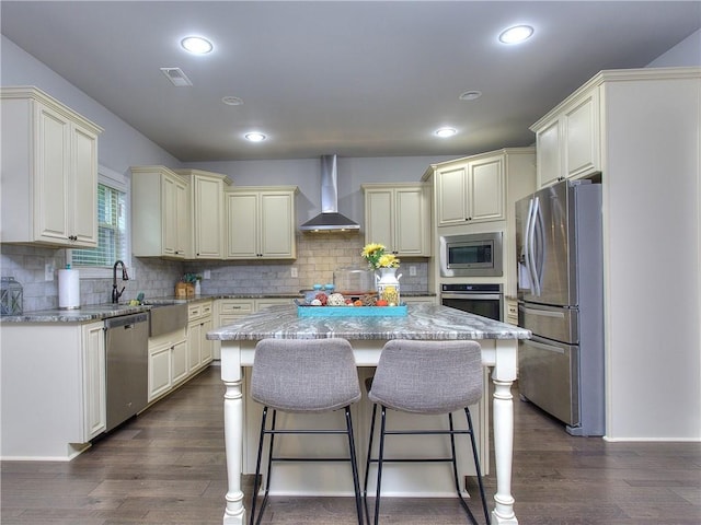 116 Chorley Run, Ellenwood, GA 30294 - kitchen with appliances with stainless steel finishes, cream cabinets, wall chimney exhaust hood, a kitchen island, and decorative backsplash