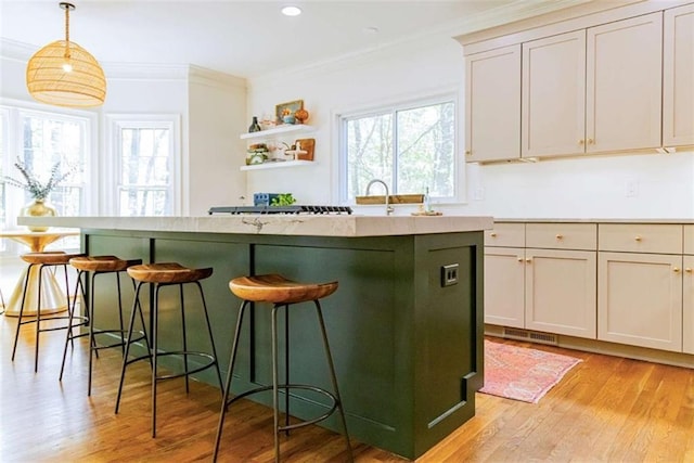 kitchen featuring a kitchen bar, open shelves, ornamental molding, and light wood-style flooring