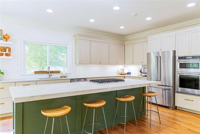 kitchen with a sink, a breakfast bar, appliances with stainless steel finishes, and a kitchen island
