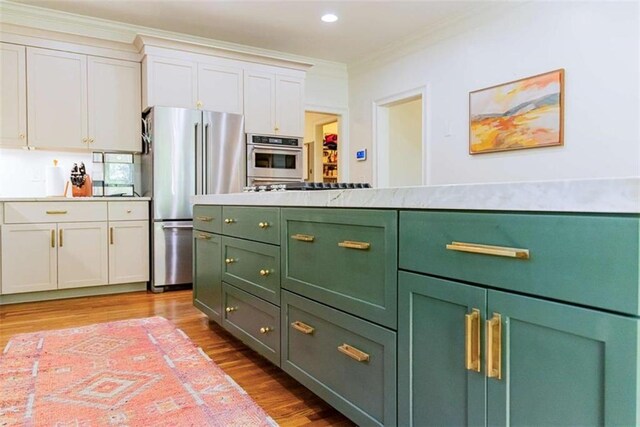 kitchen with appliances with stainless steel finishes, light wood-style floors, crown molding, white cabinetry, and green cabinets