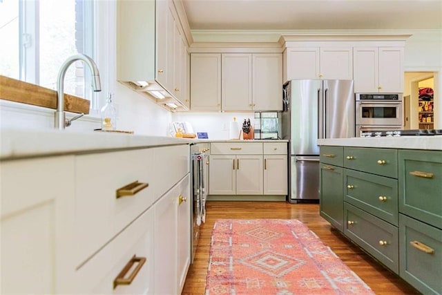 kitchen featuring green cabinets, light countertops, freestanding refrigerator, and wood finished floors