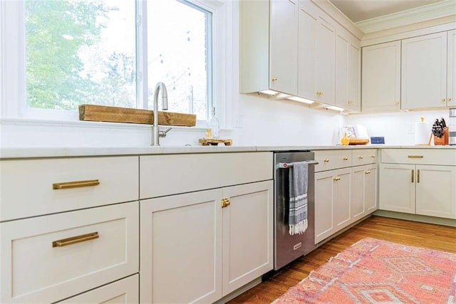 kitchen with light wood-type flooring, crown molding, a sink, and light countertops