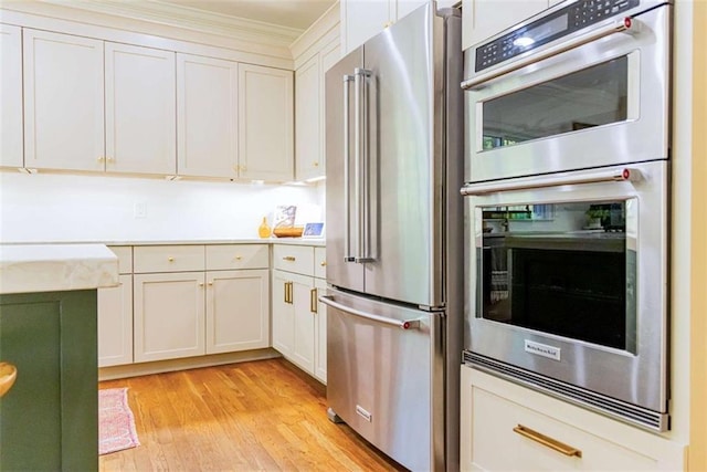 kitchen with crown molding, light wood-style floors, white cabinetry, appliances with stainless steel finishes, and light countertops