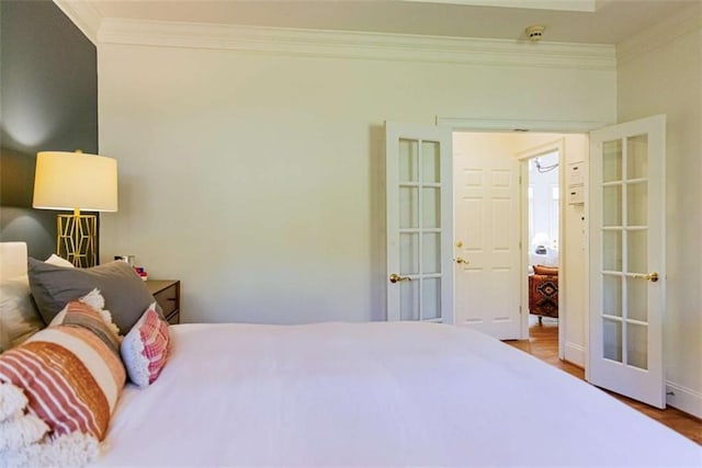 bedroom with french doors, ornamental molding, baseboards, and wood finished floors