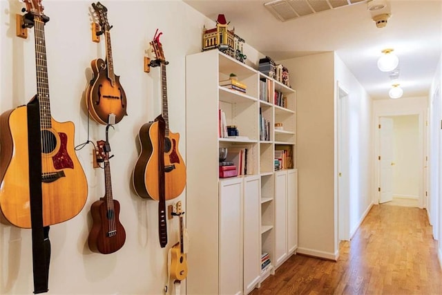 hall featuring light wood finished floors, baseboards, and visible vents