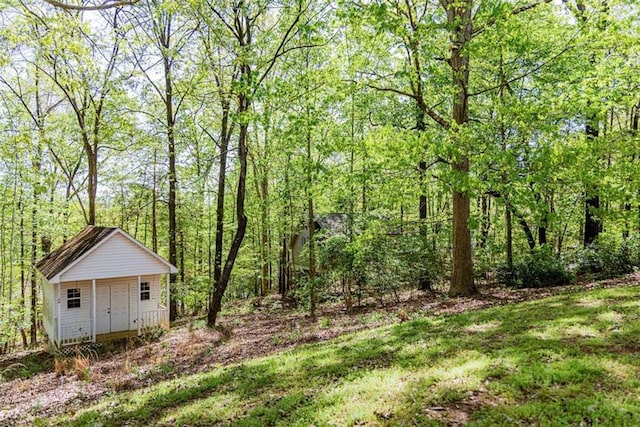 view of yard featuring a wooded view and an outdoor structure