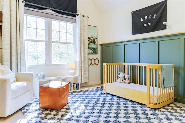 bedroom featuring a decorative wall, multiple windows, and vaulted ceiling