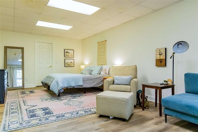 bedroom with a paneled ceiling and wood finished floors