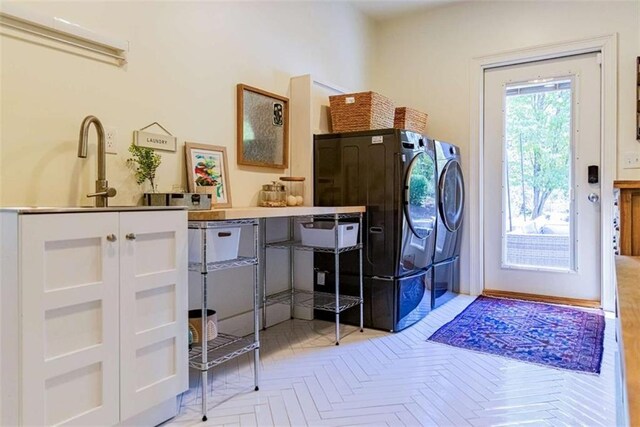 washroom with cabinet space, washer and dryer, and a sink