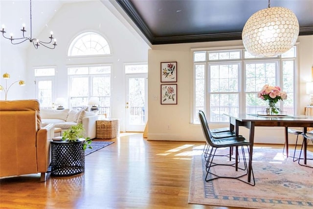dining area featuring a chandelier, a wealth of natural light, crown molding, and wood finished floors