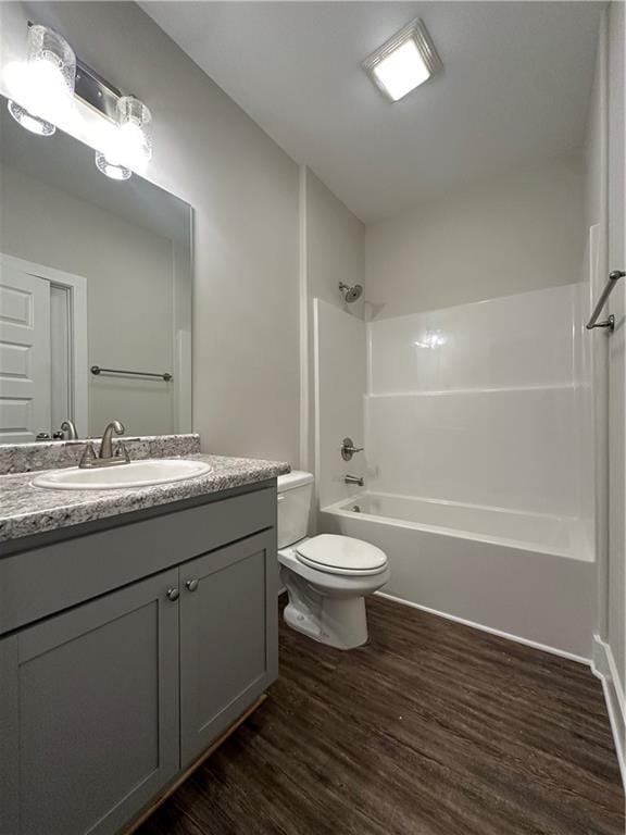 bathroom featuring vanity, washtub / shower combination, toilet, and wood finished floors