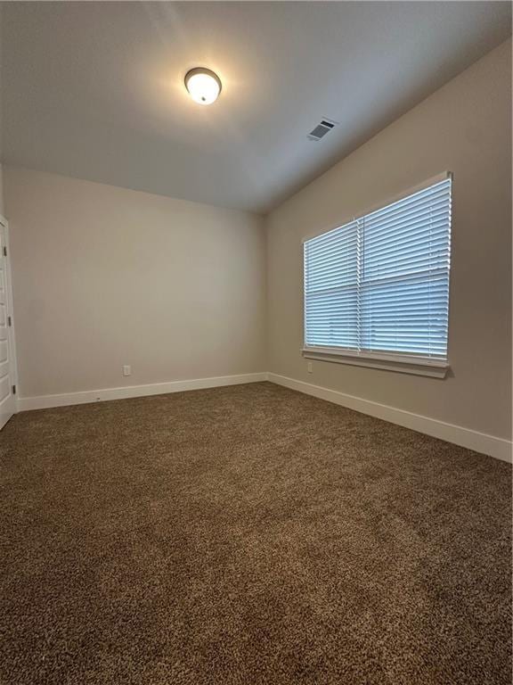 spare room with baseboards, visible vents, and dark colored carpet