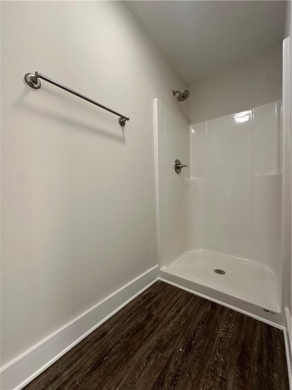 bathroom featuring a shower, baseboards, and wood finished floors