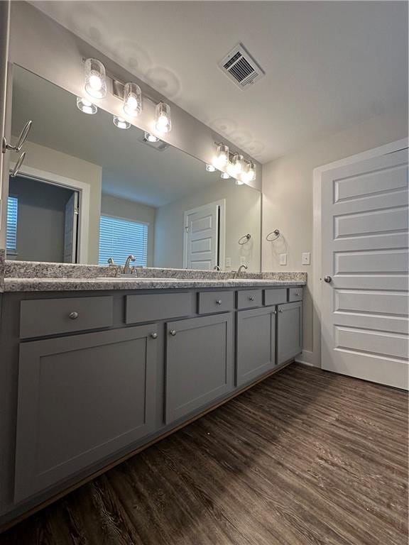 full bathroom featuring double vanity, wood finished floors, visible vents, and a sink