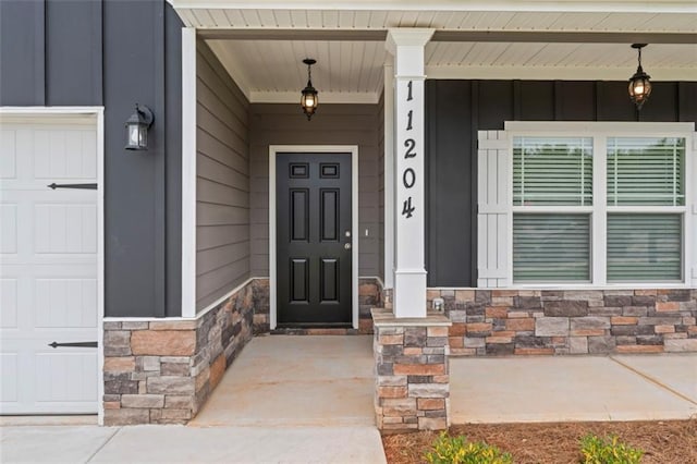 entrance to property featuring covered porch, board and batten siding, and stone siding