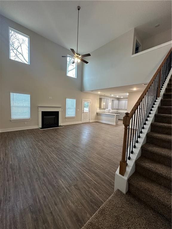 unfurnished living room with stairway, a fireplace, dark wood-type flooring, and baseboards