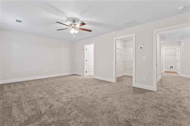 unfurnished bedroom with attic access, visible vents, baseboards, a spacious closet, and carpet flooring